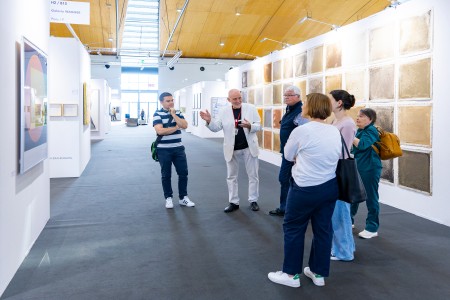 Führungen art karlsruhe Besucher schauen sich ein Gemälde an. Ein Galerist erklärt Ihnen das Bild.